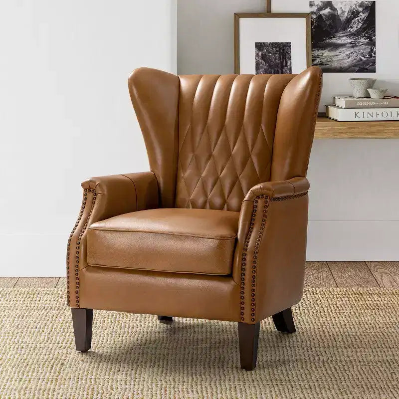 Fauteuil à oreilles en cuir véritable avec clous décoratifs et pieds fuselés en bois massif