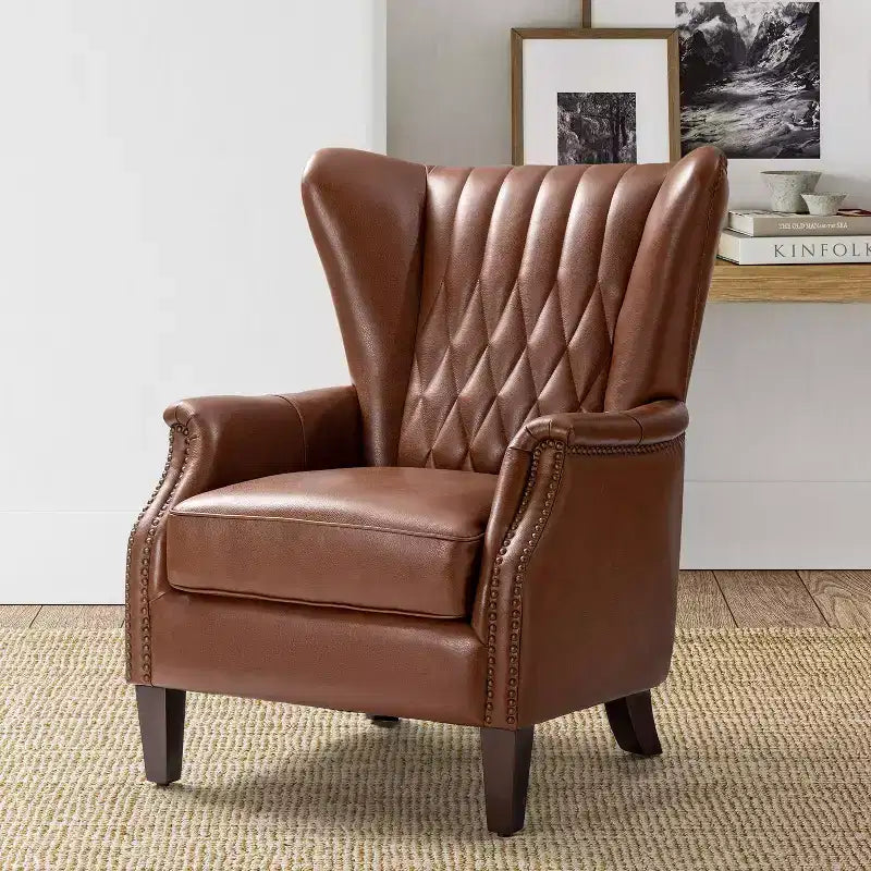 Fauteuil à oreilles en cuir véritable avec clous décoratifs et pieds fuselés en bois massif